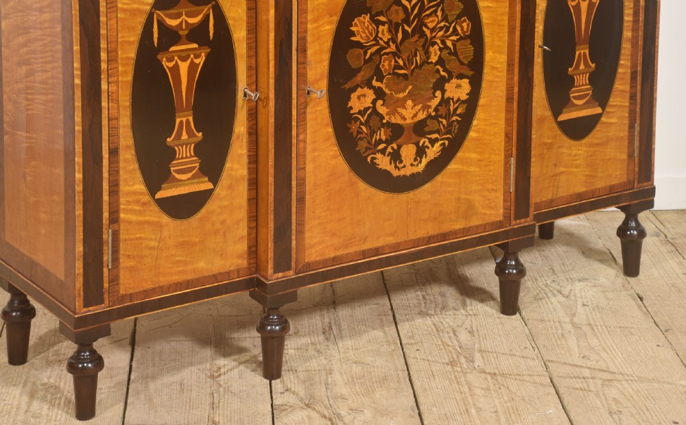A Sheraton Revival satinwood sideboard with three upper drawers and three cupboard doors featuring oval marquetry panels of flowers and urns. View III