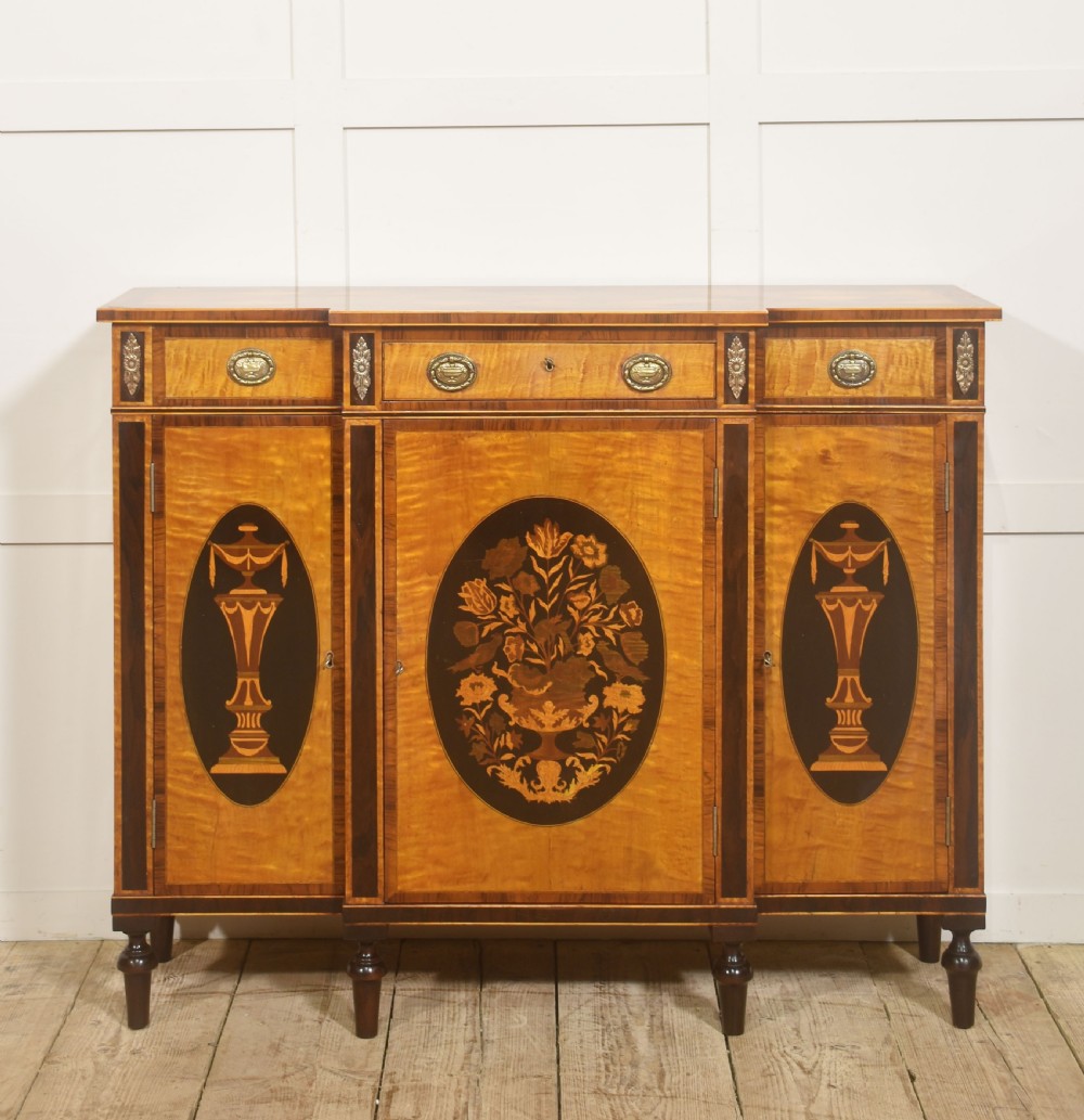 A Sheraton Revival satinwood sideboard with three upper drawers and three cupboard doors featuring oval marquetry panels of flowers and urns. View XI