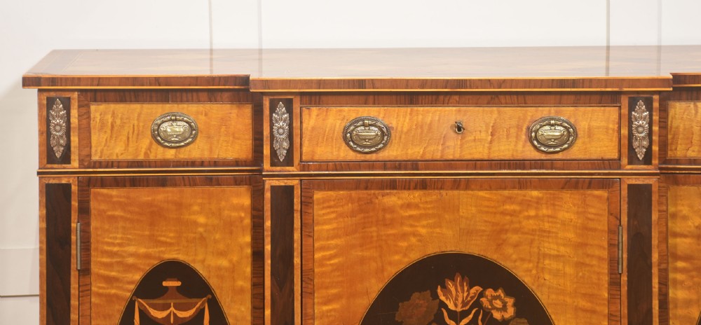 A Sheraton Revival satinwood sideboard with three upper drawers and three cupboard doors featuring oval marquetry panels of flowers and urns. View XII