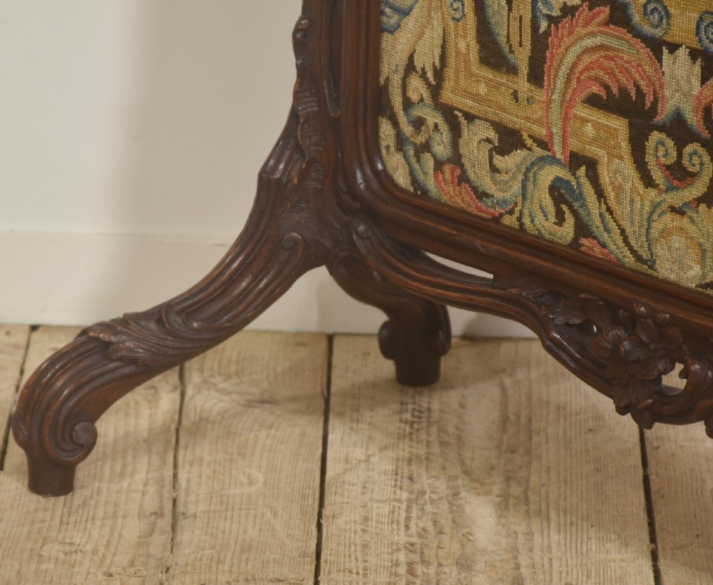 An ornate dark carved oak fire screen featuring a central needlepoint tapestry panel depicting a figure framed by elaborate scrollwork. View III