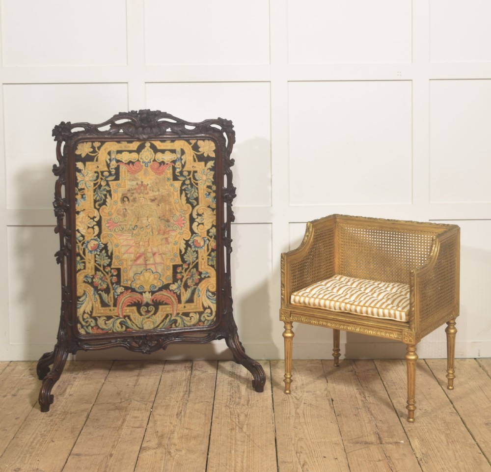 An ornate dark carved oak fire screen featuring a central needlepoint tapestry panel depicting a figure framed by elaborate scrollwork. View XII
