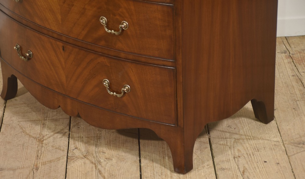 A tall George III style mahogany serpentine chest of drawers featuring flame mahogany grain and brass swan-neck handles. View V