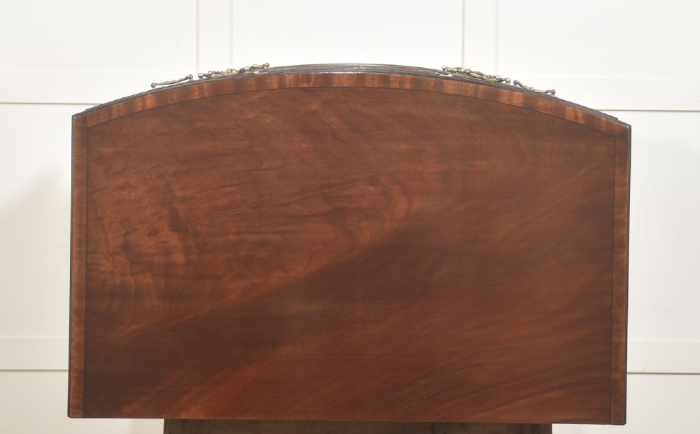 A tall George III style mahogany serpentine chest of drawers featuring flame mahogany grain and brass swan-neck handles. View XI
