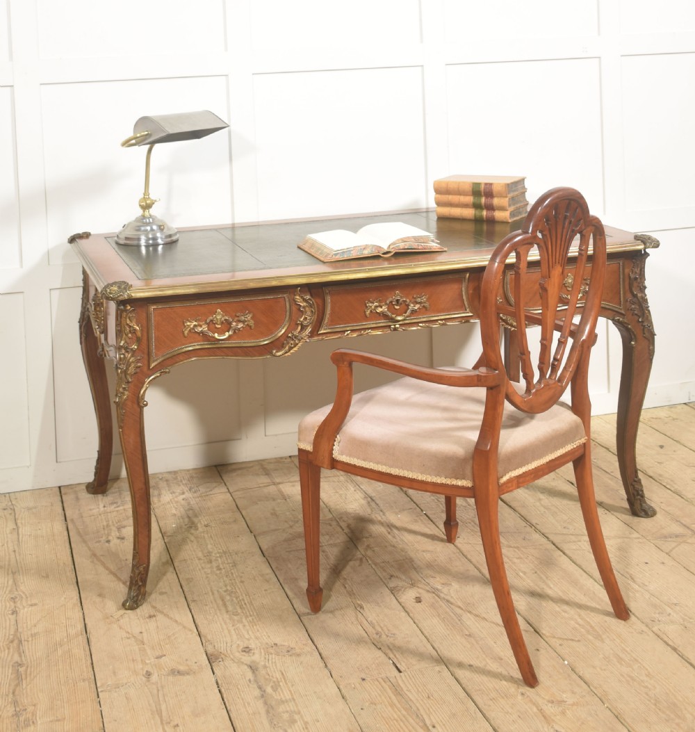 A French Louis XV style wooden bureau plat featuring three frieze drawers, gilt-bronze ormolu mounts, cabriole legs, and a green leather writing surface. View III