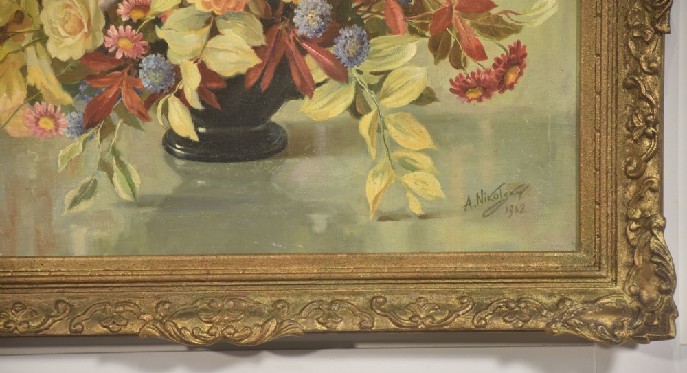 A framed oil painting on canvas depicting a still life arrangement of orange and yellow autumn flowers in a dark vase set within an ornate carved gilt frame. View IV