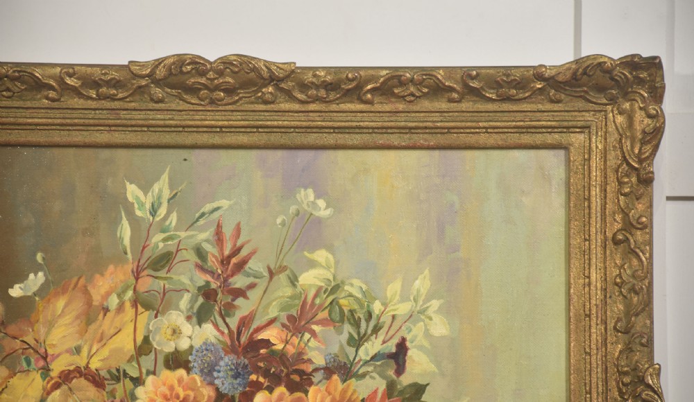 A framed oil painting on canvas depicting a still life arrangement of orange and yellow autumn flowers in a dark vase set within an ornate carved gilt frame. View VI