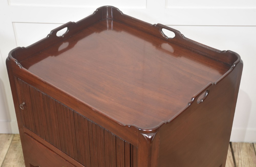 A pair of dark warm mahogany bedside cabinets featuring gallery tops with cutout handles, reeded tambour doors, and single lower drawers with brass handles. View III