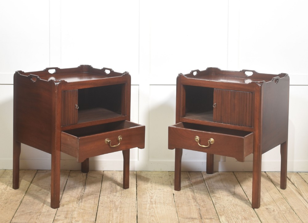 A pair of dark warm mahogany bedside cabinets featuring gallery tops with cutout handles, reeded tambour doors, and single lower drawers with brass handles. View IV
