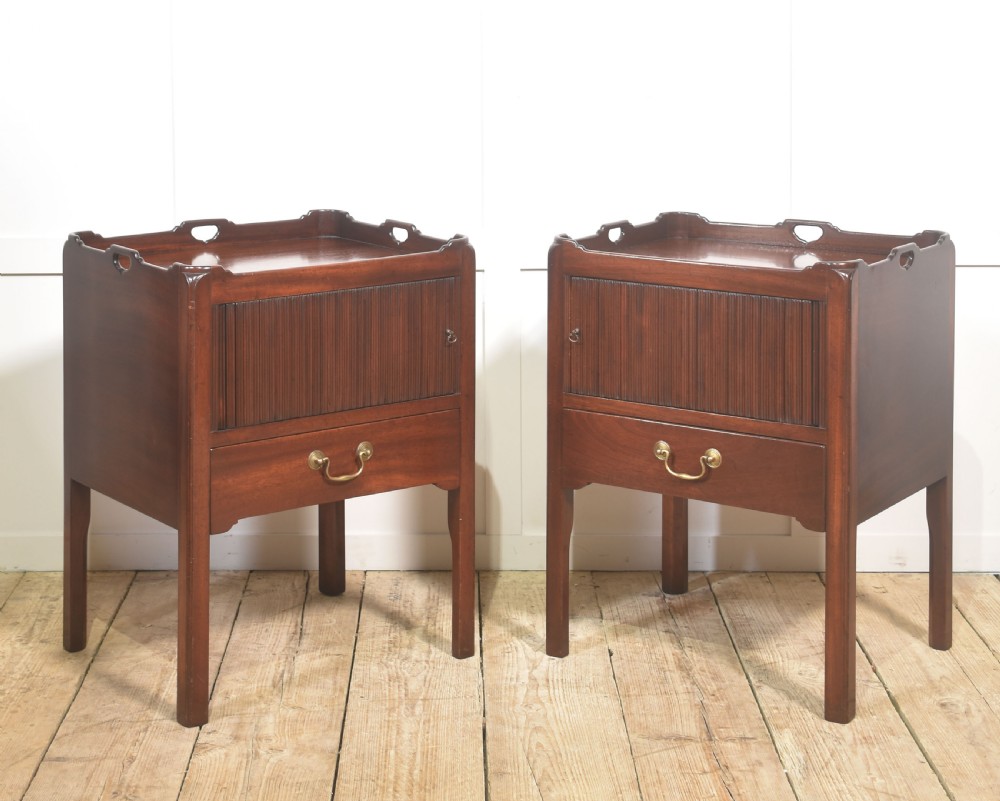 A pair of dark warm mahogany bedside cabinets featuring gallery tops with cutout handles, reeded tambour doors, and single lower drawers with brass handles. View VI