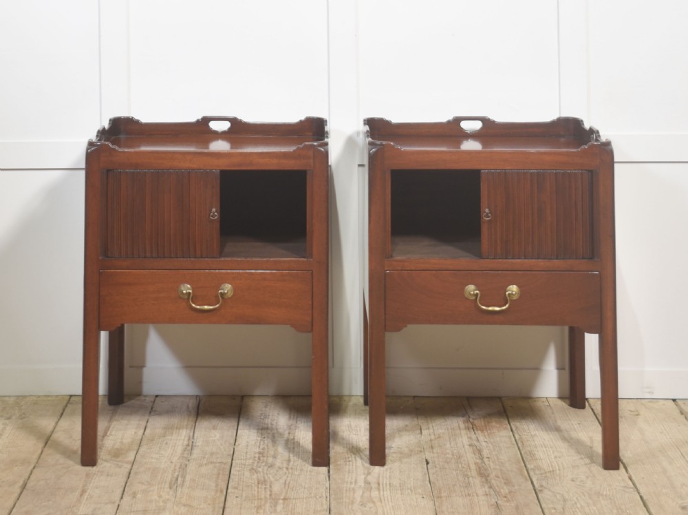 A pair of dark warm mahogany bedside cabinets featuring gallery tops with cutout handles, reeded tambour doors, and single lower drawers with brass handles. View VII