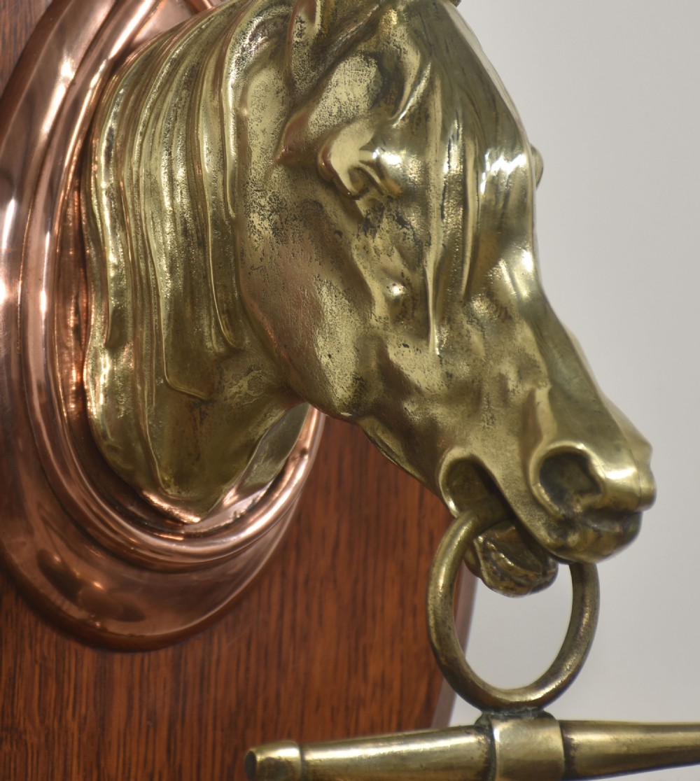 A wall-hanging oak oval plaque featuring a cast brass horse head mount supporting a circular brass dinner gong with a suspended striker. View III