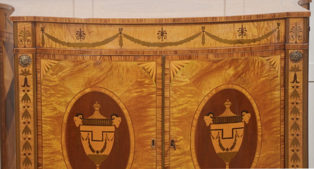 A Neoclassical demi-lune side cabinet crafted from golden satinwood featuring detailed urn marquetry inlays on two doors and tapered square legs. View II