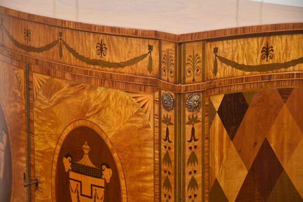 A Neoclassical demi-lune side cabinet crafted from golden satinwood featuring detailed urn marquetry inlays on two doors and tapered square legs. View XI