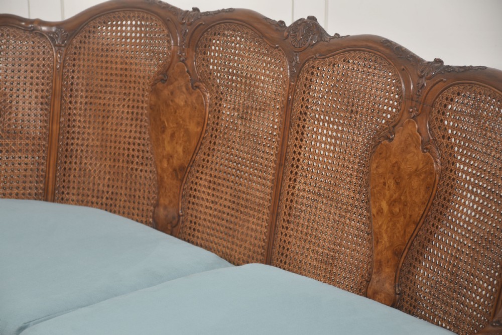 A Louis XV style carved walnut settee featuring a four-panel caned backrest, central burr walnut splats, light blue seat cushions, and carved cabriole legs. View III