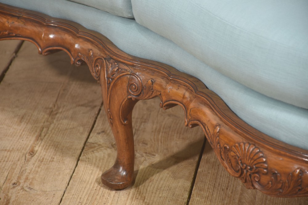 A Louis XV style carved walnut settee featuring a four-panel caned backrest, central burr walnut splats, light blue seat cushions, and carved cabriole legs. View VII