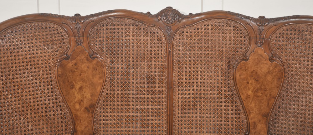 A Louis XV style carved walnut settee featuring a four-panel caned backrest, central burr walnut splats, light blue seat cushions, and carved cabriole legs. View XII