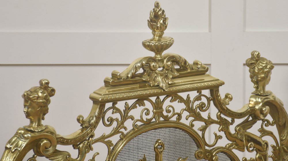An ornate cast brass free-standing fire screen featuring pierced Rococo scrollwork, a mesh panel with torch and ribbon detailing, and scrolled feet. View XI
