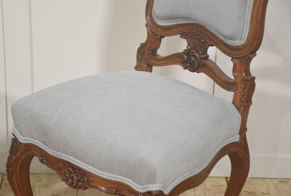 A pair of carved walnut Louis XV style side chairs with light grey upholstery on the seats and padded backrests. View III