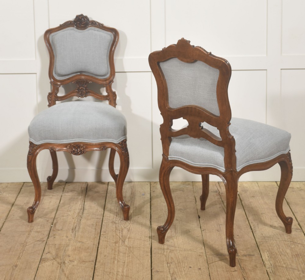 A pair of carved walnut Louis XV style side chairs with light grey upholstery on the seats and padded backrests. View VII