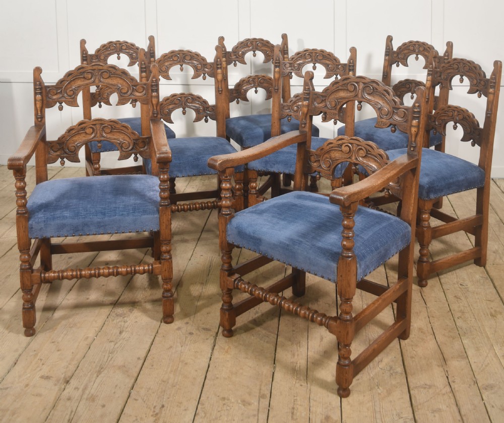 A set of eight Jacobean Revival carved oak dining chairs with blue velvet upholstered seats, including two carver armchairs and six side chairs. View II