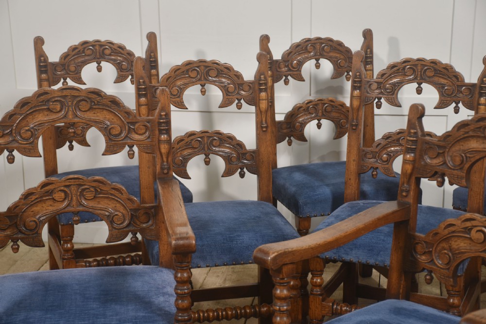 A set of eight Jacobean Revival carved oak dining chairs with blue velvet upholstered seats, including two carver armchairs and six side chairs. View III