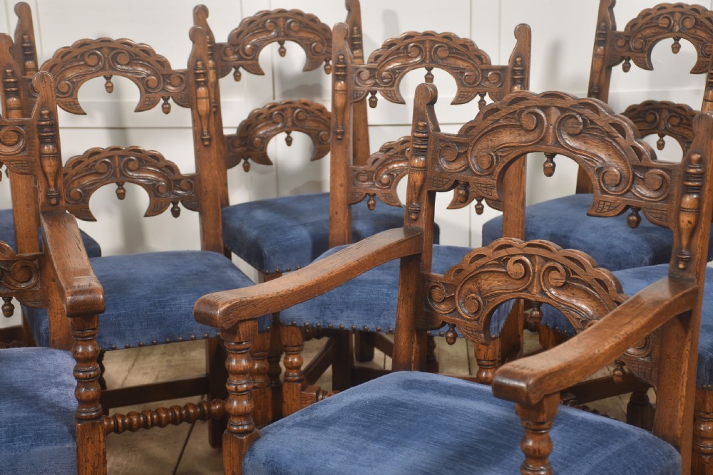 A set of eight Jacobean Revival carved oak dining chairs with blue velvet upholstered seats, including two carver armchairs and six side chairs. View IV