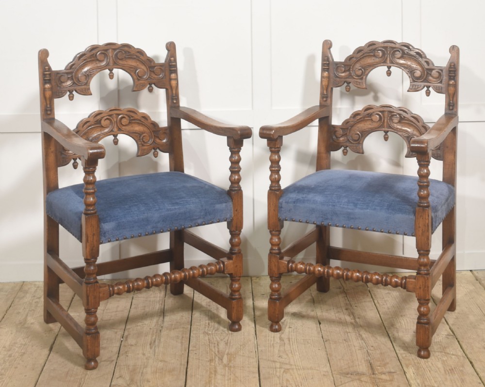 A set of eight Jacobean Revival carved oak dining chairs with blue velvet upholstered seats, including two carver armchairs and six side chairs. View V