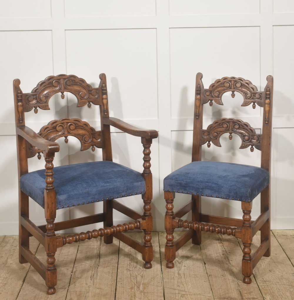 A set of eight Jacobean Revival carved oak dining chairs with blue velvet upholstered seats, including two carver armchairs and six side chairs. View VIII