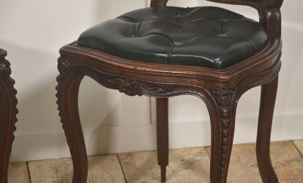 A pair of carved walnut side chairs in the Louis XV style, featuring woven cane backs, dark leather button-tufted seats, and cabriole legs. View IV