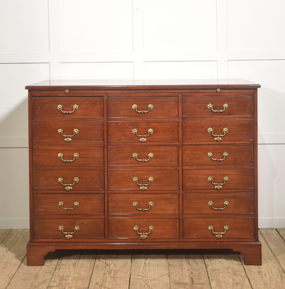 A Georgian style mahogany filing cabinet featuring a bank of multiple small drawers with brass swan-neck handles on a bracket foot base.