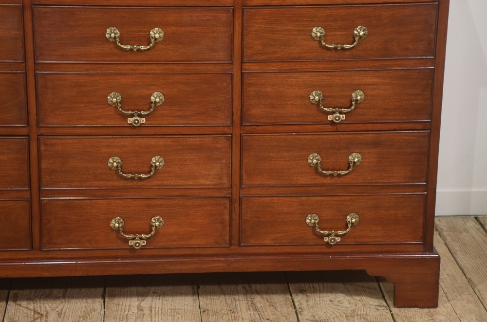 A Georgian style mahogany filing cabinet featuring a bank of multiple small drawers with brass swan-neck handles on a bracket foot base. View II