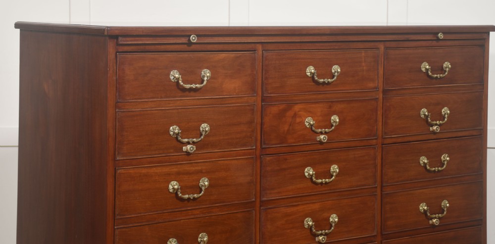 A Georgian style mahogany filing cabinet featuring a bank of multiple small drawers with brass swan-neck handles on a bracket foot base. View VI
