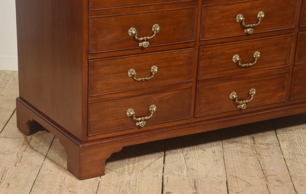 A Georgian style mahogany filing cabinet featuring a bank of multiple small drawers with brass swan-neck handles on a bracket foot base. View VIII