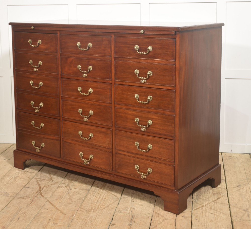 A Georgian style mahogany filing cabinet featuring a bank of multiple small drawers with brass swan-neck handles on a bracket foot base. View IX