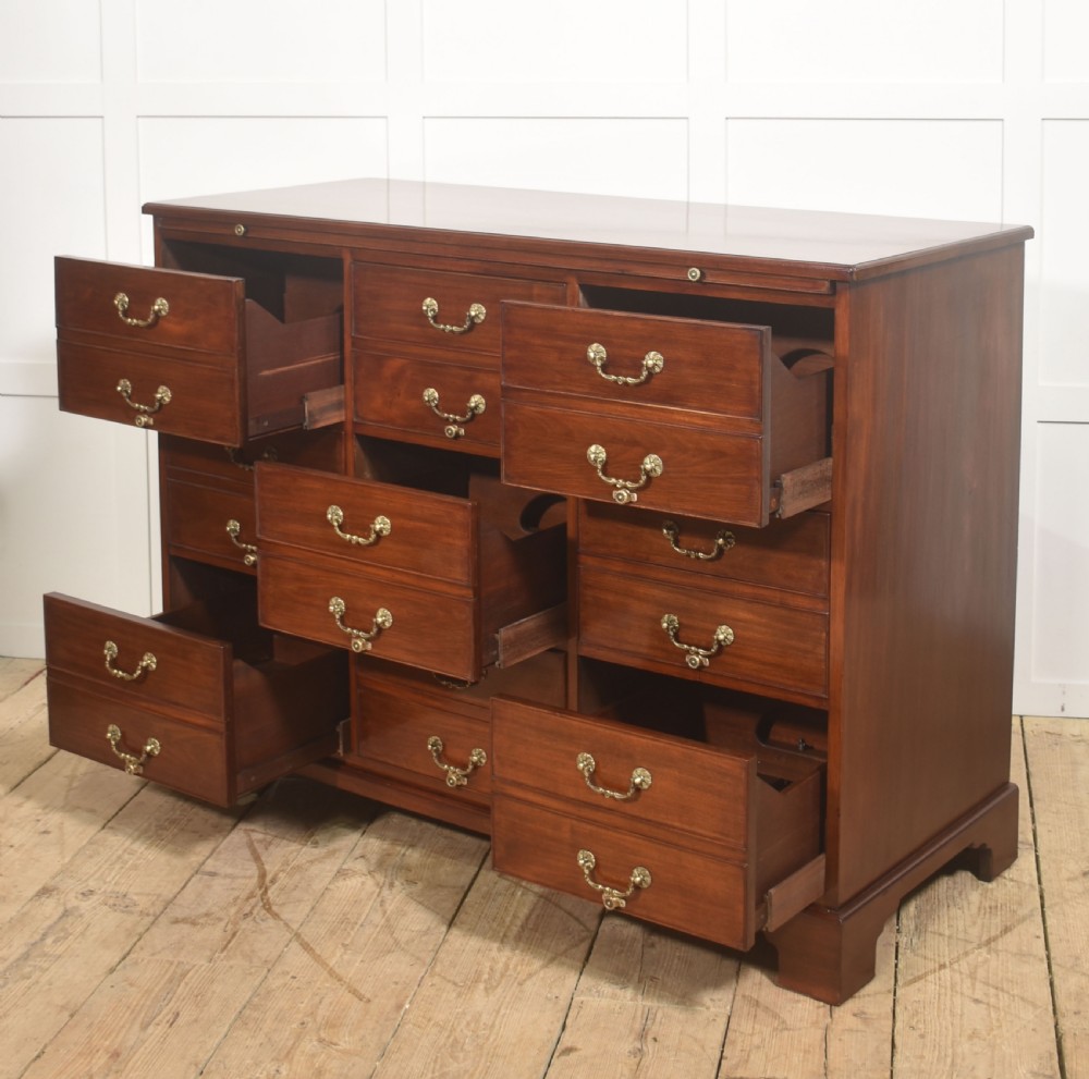 A Georgian style mahogany filing cabinet featuring a bank of multiple small drawers with brass swan-neck handles on a bracket foot base. View XI