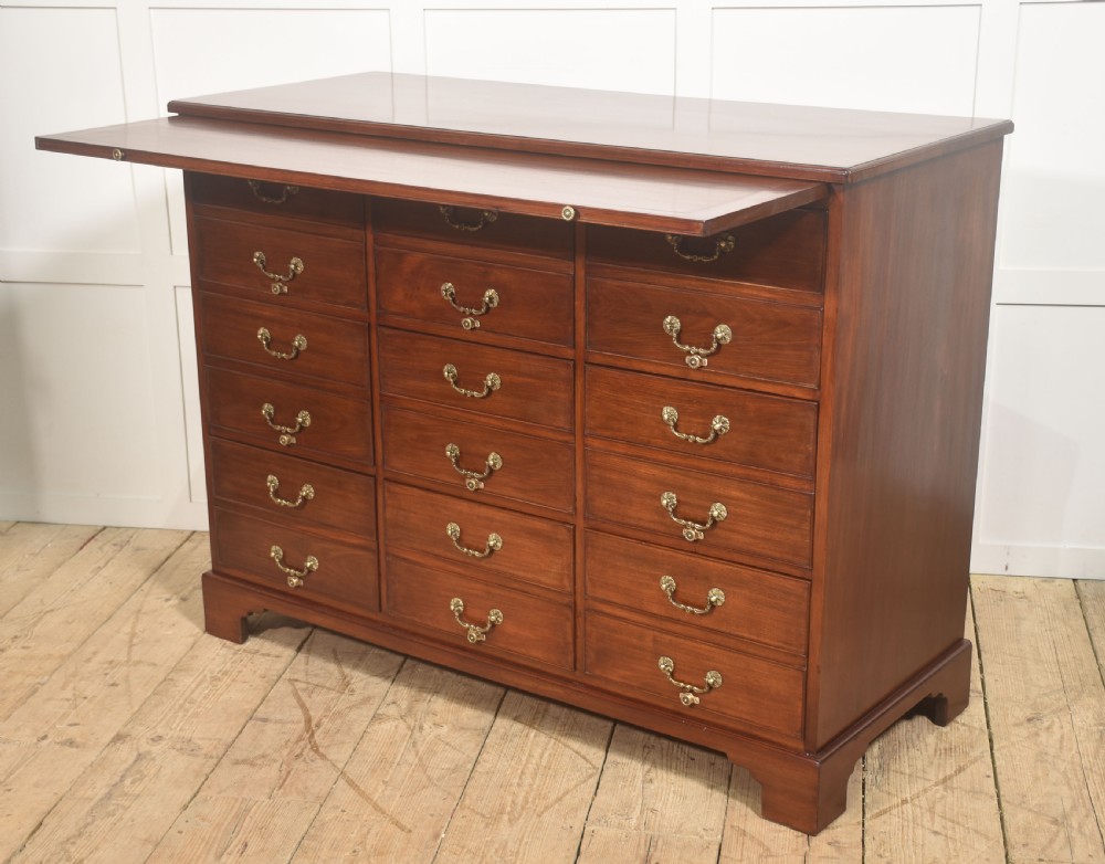 A Georgian style mahogany filing cabinet featuring a bank of multiple small drawers with brass swan-neck handles on a bracket foot base. View XIII