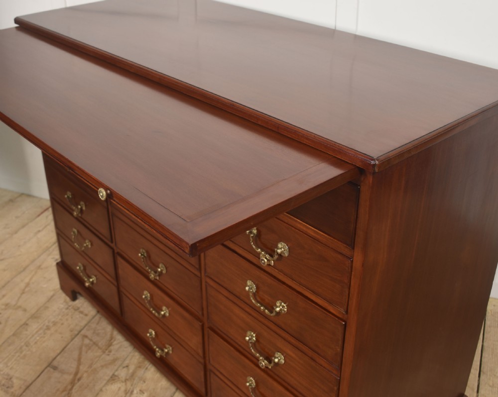 A Georgian style mahogany filing cabinet featuring a bank of multiple small drawers with brass swan-neck handles on a bracket foot base. View XIV