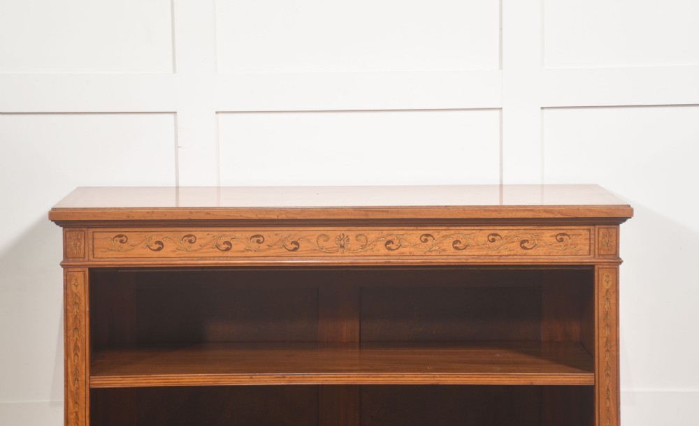 A low satinwood open bookcase featuring three shelves and a decorative inlaid floral frieze across the top. View X