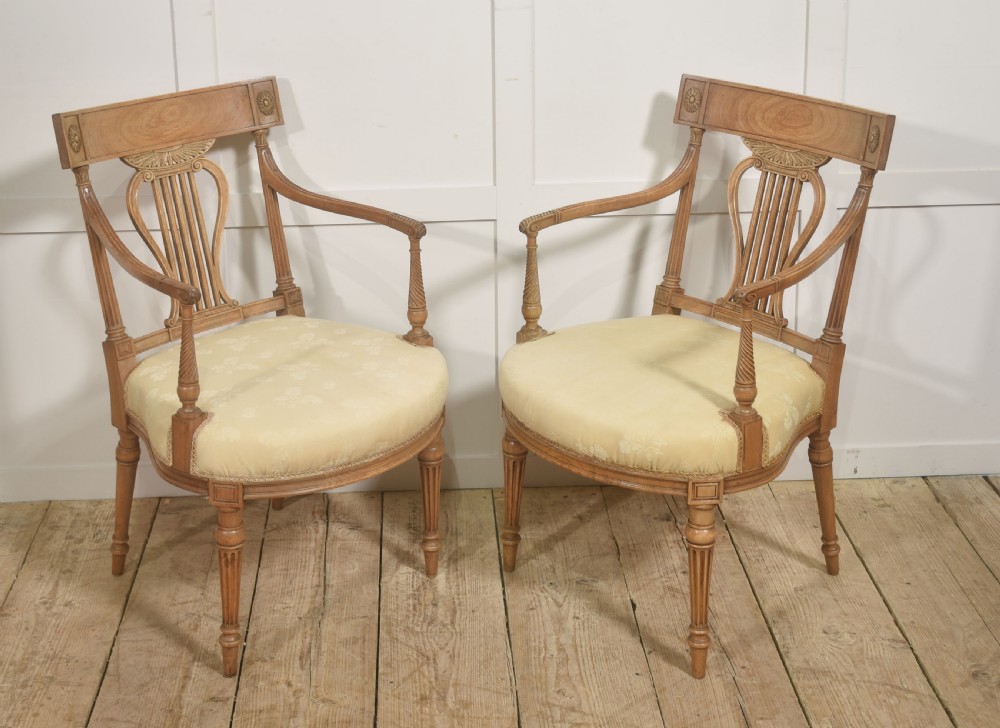 A pair of light mahogany open armchairs featuring lyre-designed back splats, carved rosettes on the top rails, fluted turned legs, and cream-patterned upholstered seats. View IV