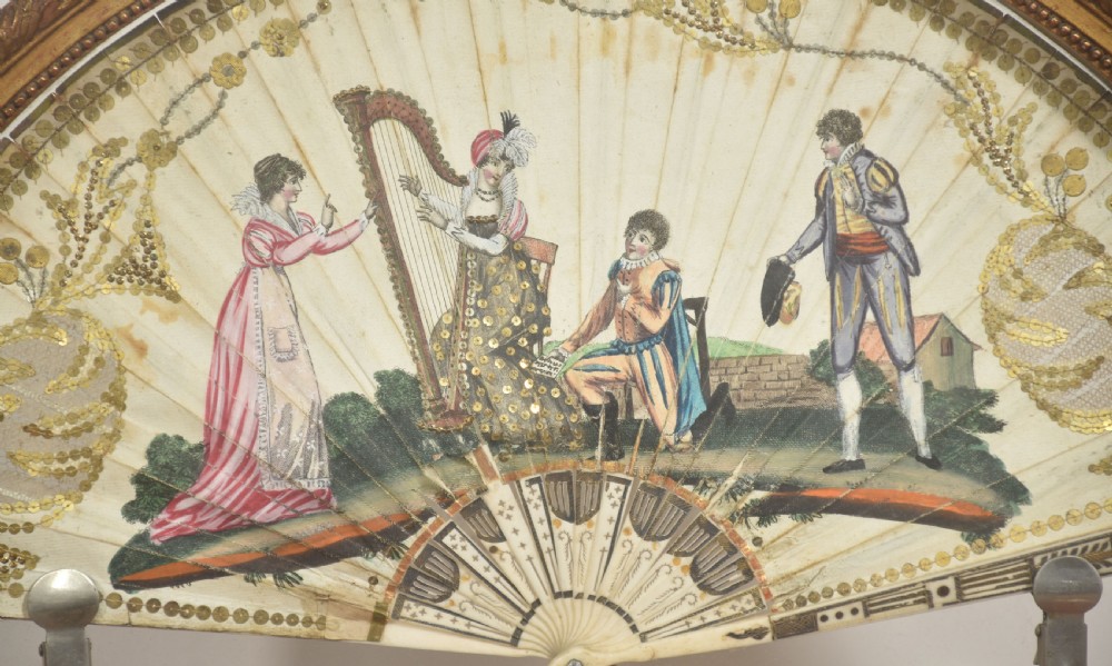 A hand-painted folding fan featuring a pastoral musical scene mounted inside a glazed giltwood frame on a turned pedestal. View III