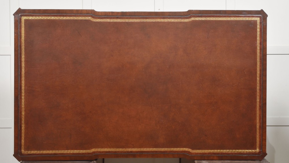 A large mahogany pedestal desk featuring a leather writing surface, multiple drawers with brass swan-neck handles, and carved corner details. View XVIII