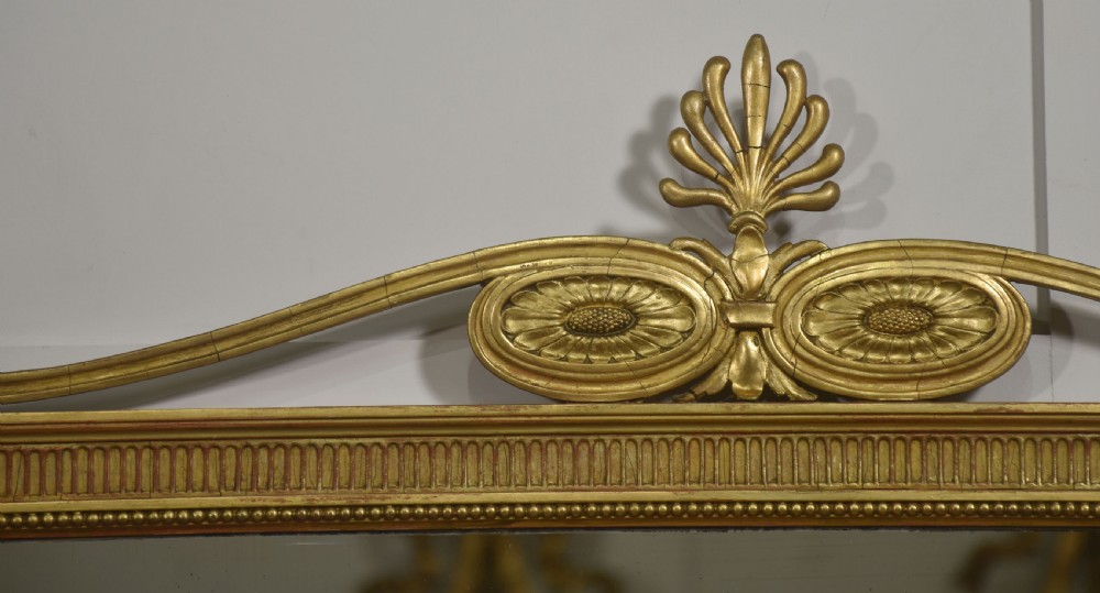 A horizontal Neoclassical giltwood panelled overmantel mirror featuring a top palmette crest, fluted frame, and sectioned glass plates. View II