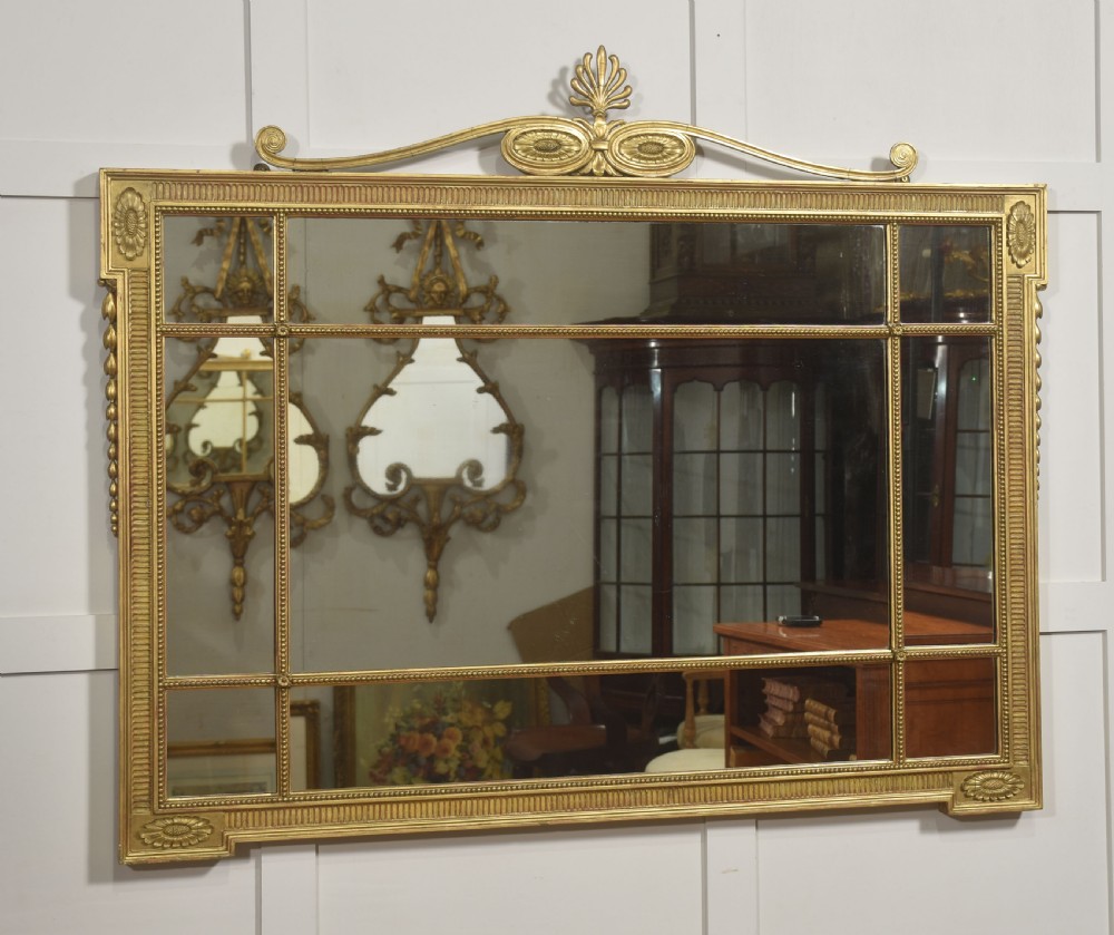 A horizontal Neoclassical giltwood panelled overmantel mirror featuring a top palmette crest, fluted frame, and sectioned glass plates. View VI
