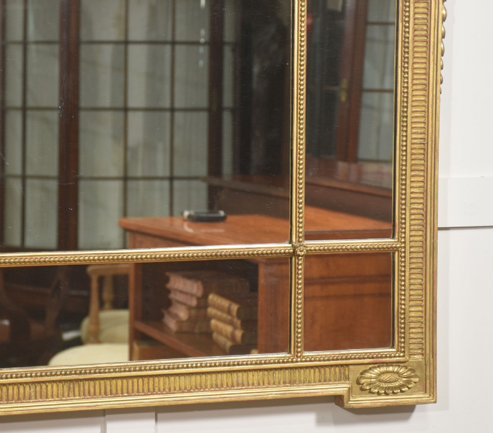 A horizontal Neoclassical giltwood panelled overmantel mirror featuring a top palmette crest, fluted frame, and sectioned glass plates. View VII