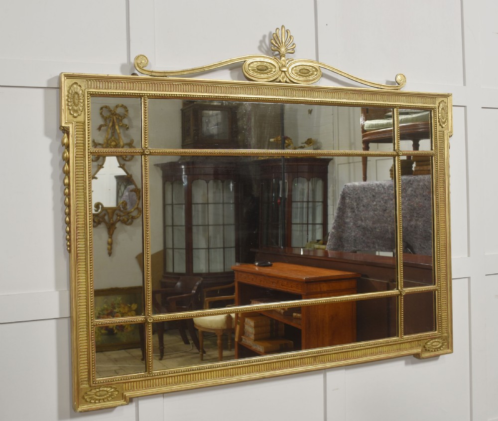 A horizontal Neoclassical giltwood panelled overmantel mirror featuring a top palmette crest, fluted frame, and sectioned glass plates. View VIII
