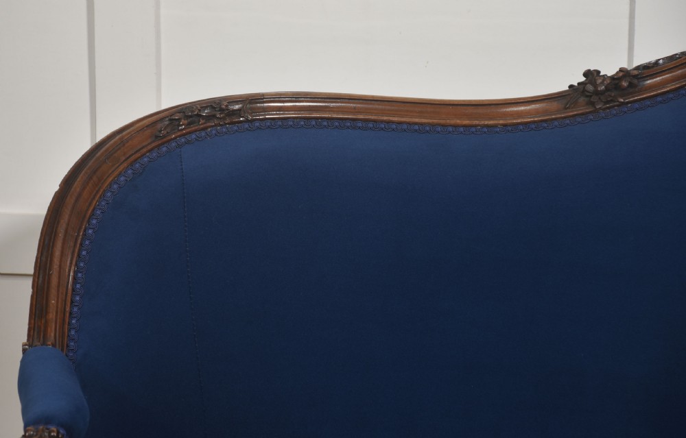 A 19th-century carved walnut settee featuring deep blue velvet upholstery, a serpentine crest rail, and hand-carved cabriole legs on small castors. View III