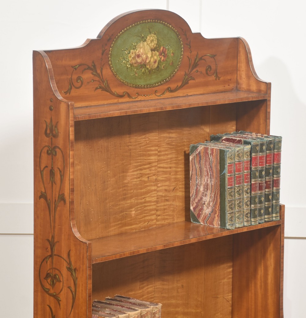 An Aesthetic Movement open satinwood bookcase featuring a painted floral crest, fiddleback timber grain, and slender open shelves. View VII
