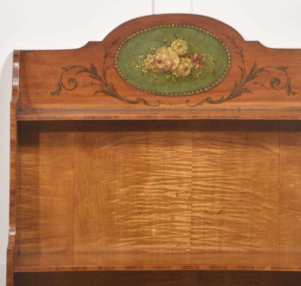 An Aesthetic Movement open satinwood bookcase featuring a painted floral crest, fiddleback timber grain, and slender open shelves. View VIII