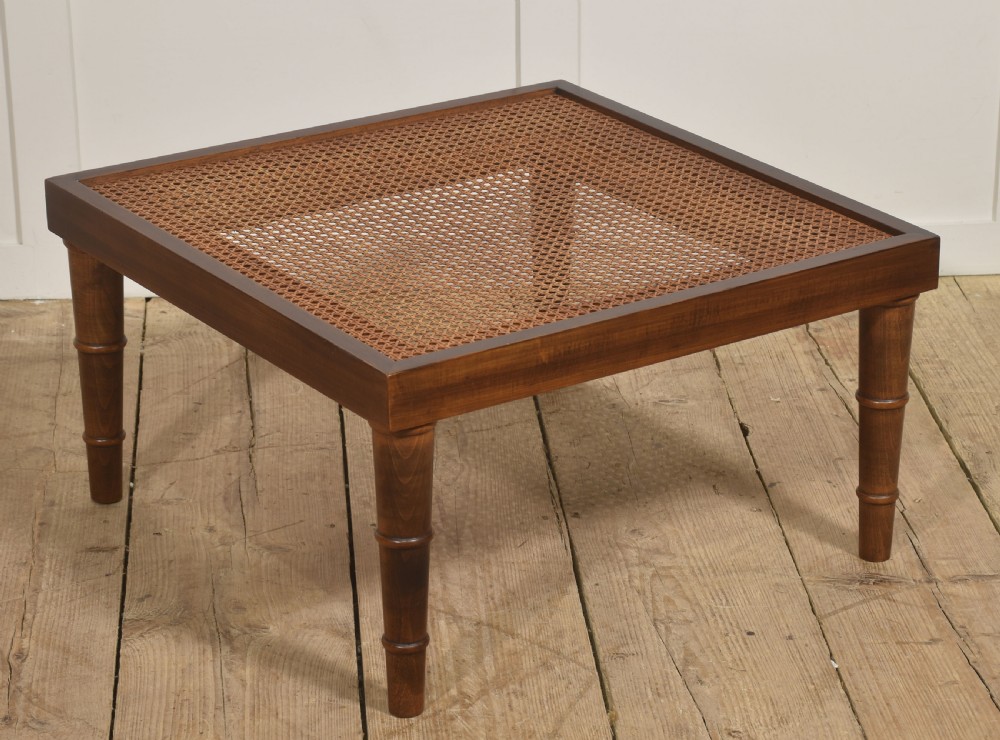 A square mahogany coffee table featuring a woven cane top set within a solid wood frame and supported by turned legs. View II
