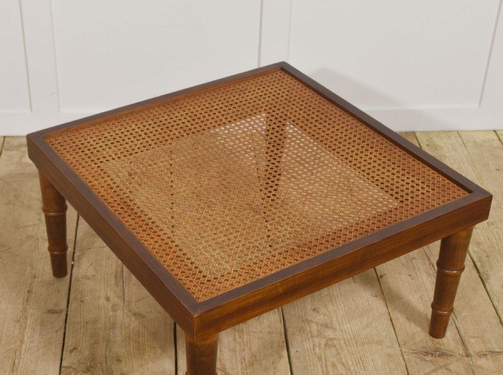 A square mahogany coffee table featuring a woven cane top set within a solid wood frame and supported by turned legs. View IV